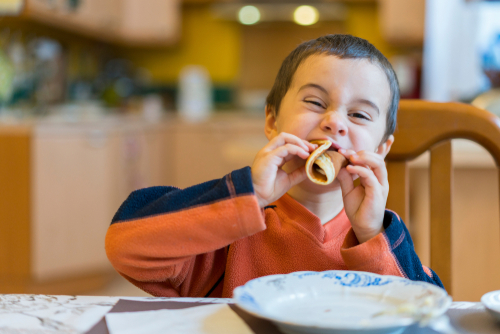 Smiling boy eating at a dinner table