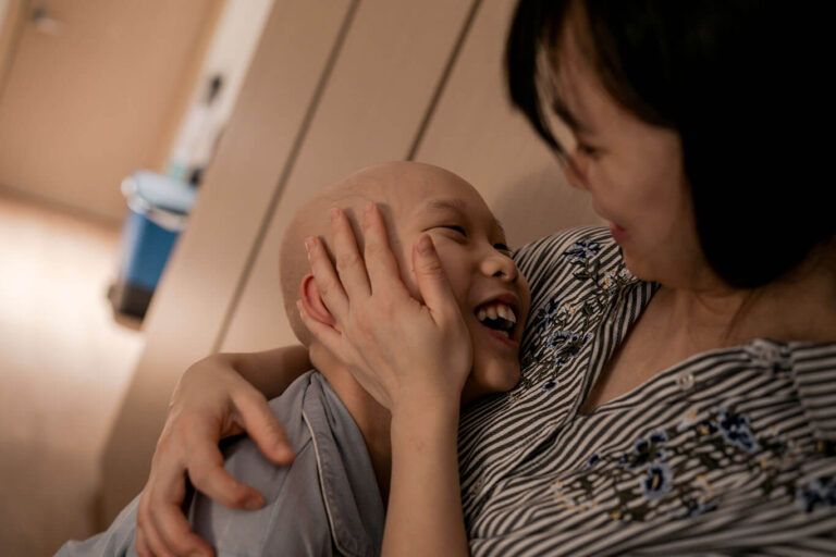 Mother and child laughing together cheek to cheek
