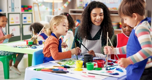 Volunteer painting with a group of children at a craft table